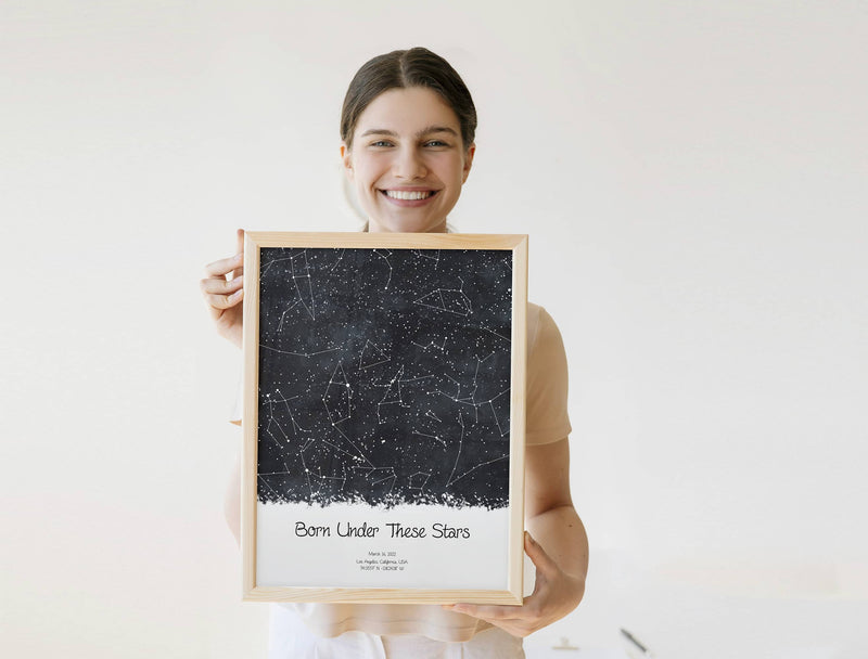 Women holding a custom black star map poster, created by date and location with a custom quote 